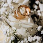 Golden wedding rings on the white rose from the wedding bouquet